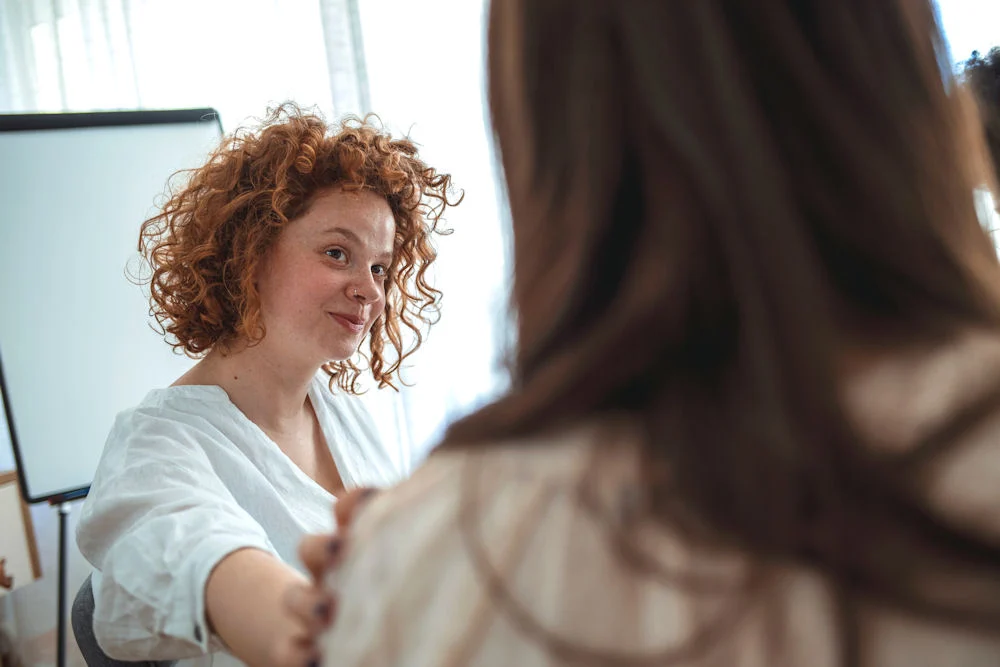 woman putting her hand on another's shoulder during therapy